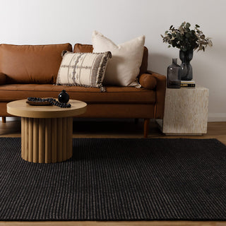 Natura Black Wool Rug styled in living room with tan leather sofa