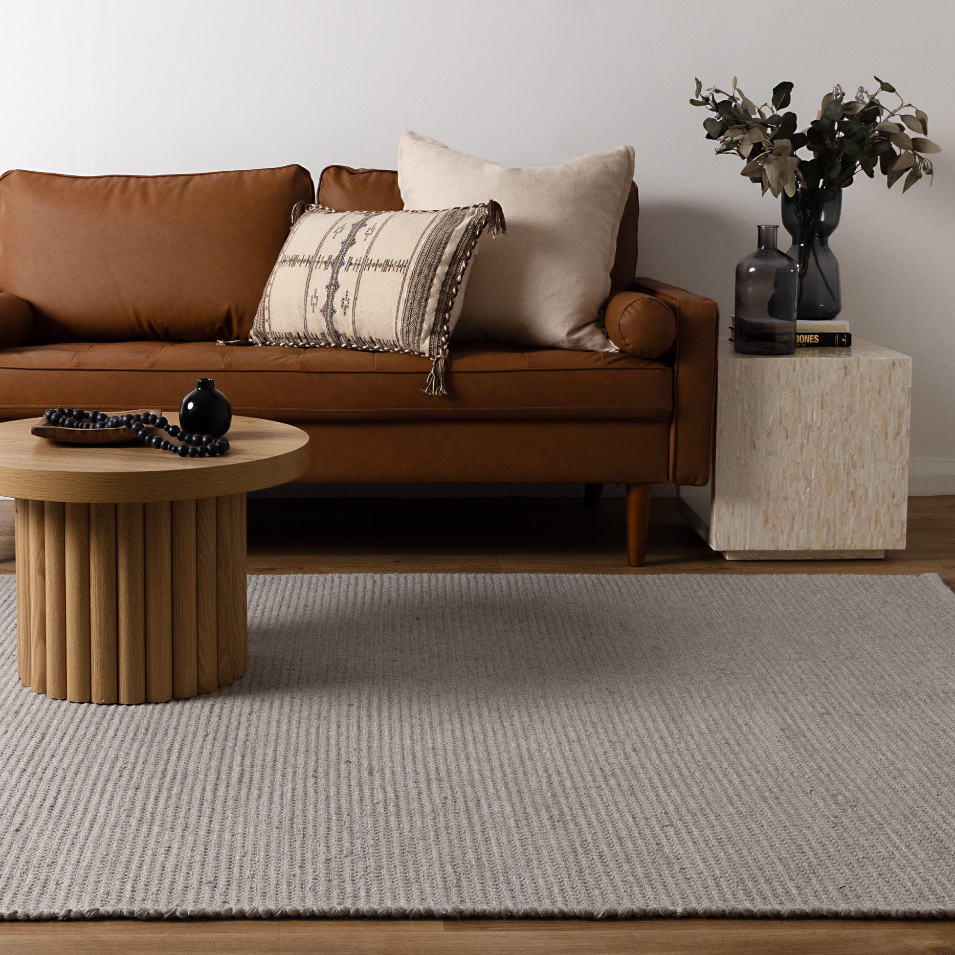 Natura Grey Wool Rug in living room with tan leather sofa